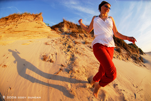 woman running down sand dune on Island of Juist, Germany. © Cody Duncan Photography