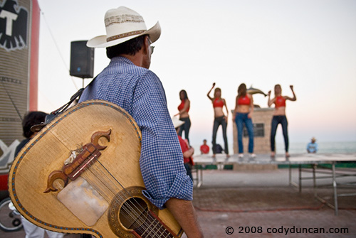 2008 Baja 250 San Felipe. Street musician watching women dancers during pre-race festival.  © Cody Duncan Photography