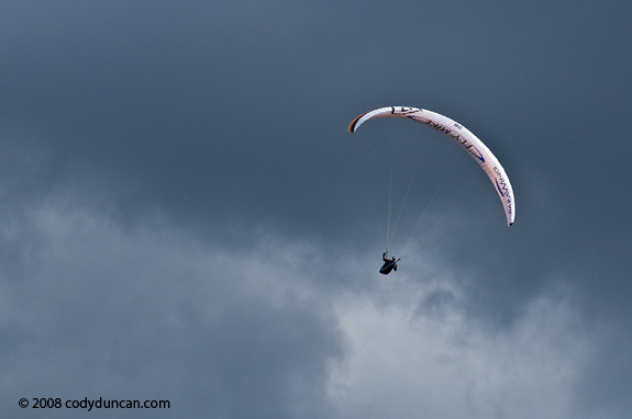 Paraglider flying in air with stormy sky, Germany. Cody Duncan travel stock photography