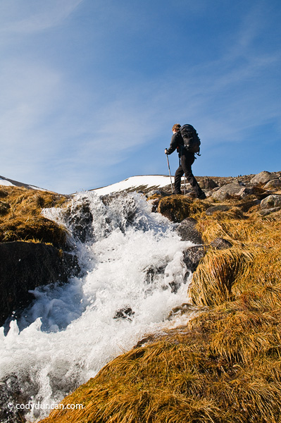 Travel stock photography: Female backpacker hikes near running river in cairngorm mountains, Scotland
