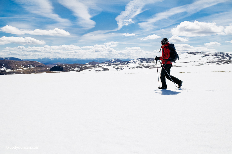 Adventure stock photography: Female hiker crosses snowfield near summit of Cairn Lochan in the Cairngorm mountains, Scotland