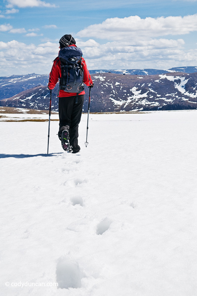 Adventure stock photography: Female hiker crosses snowfield near summit of Cairn Lochan in the Cairngorm mountains, Scotland