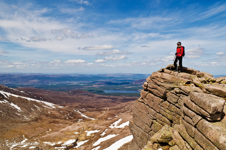 lifestyle stock travel photography: Female hiker stands on cliff near Cairn Gorm in the Cairngorm mountains of Scotland