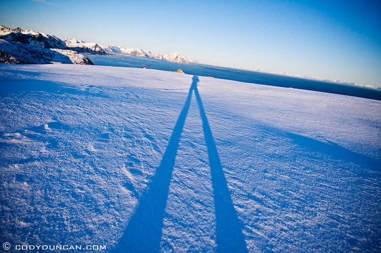 Lofoten islands winter mountain photo: shadow of hiker across snowy landscape
