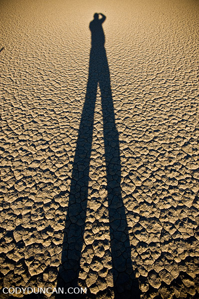 travel and landscape photographer Cody Duncan stands on dry lake bed at Racetrack playa, Death Valley, California