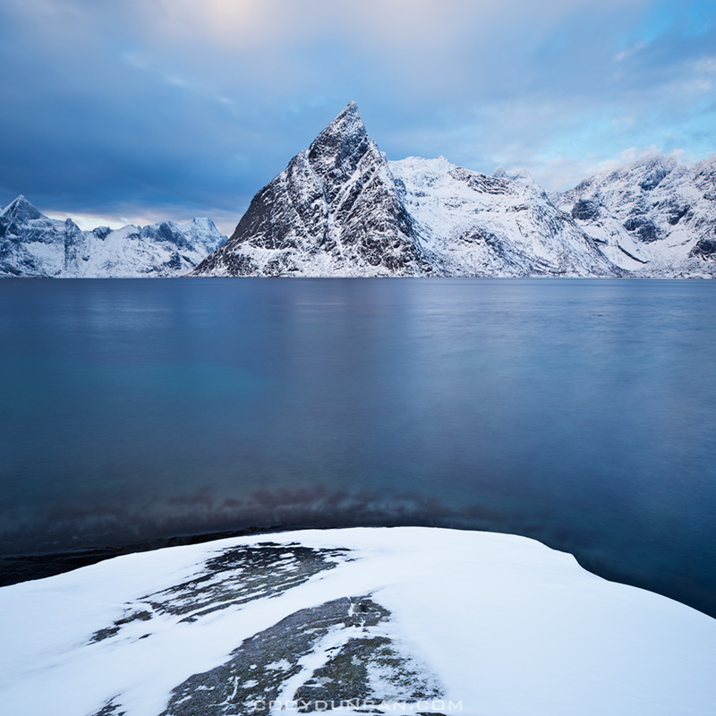 Olstind mountain peak rises from fjord, Lofoten Islands, Norway